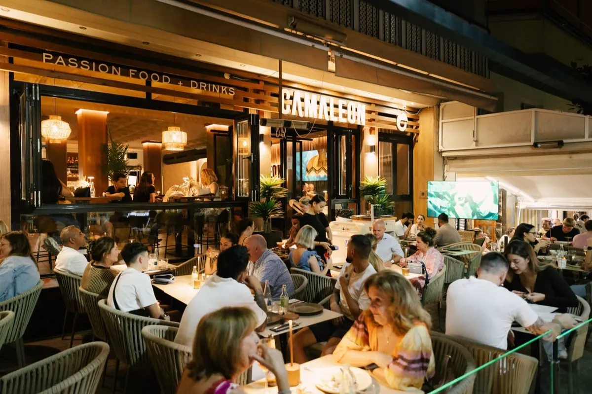 Terraza y fachada de Restaurante Camaleón Marbella de noche, con mesas llenas y ambiente animado en el centro de Marbella.